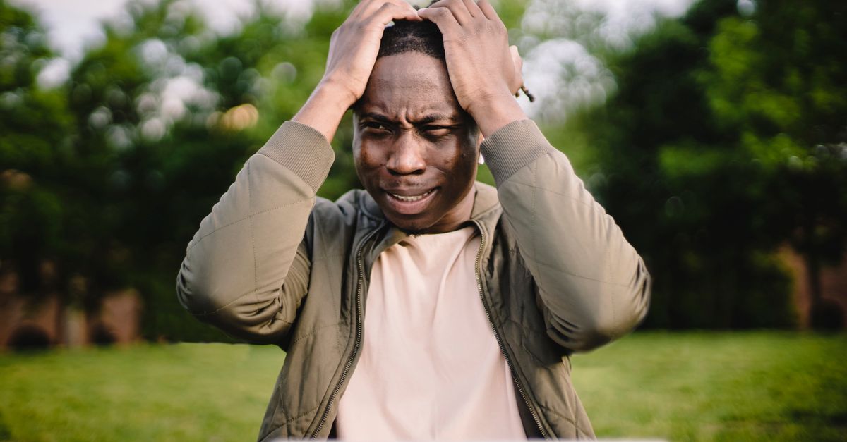 person looking frustrated at a router while laptop shows buffering icon