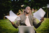 快乐的人在公园里拿着文件远程工作，享受着成功的喜悦