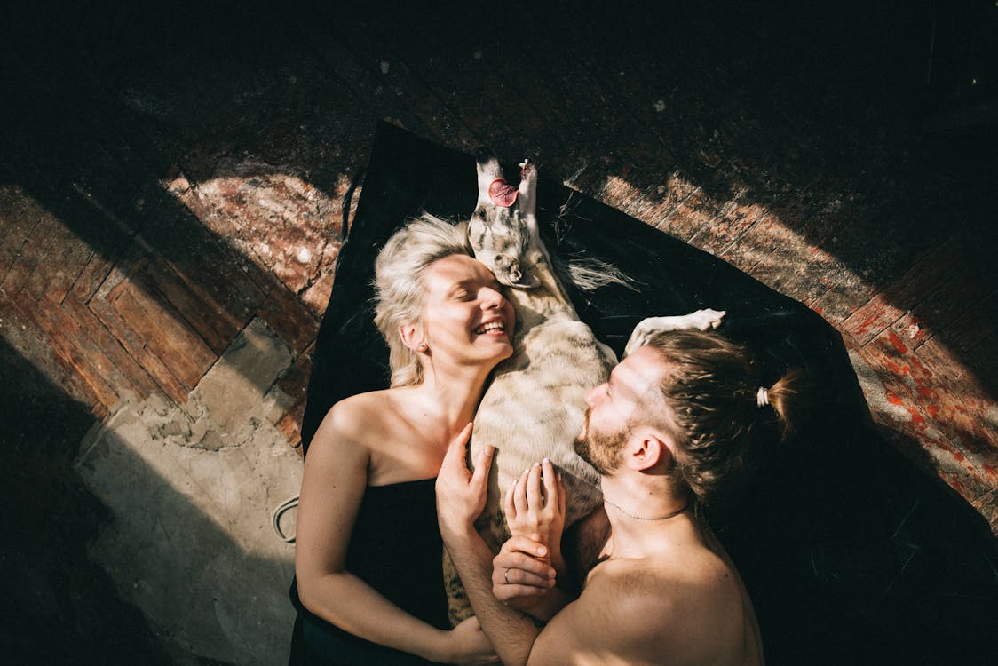 Free Couple Lying Down and Hugging their Dog Stock Photo