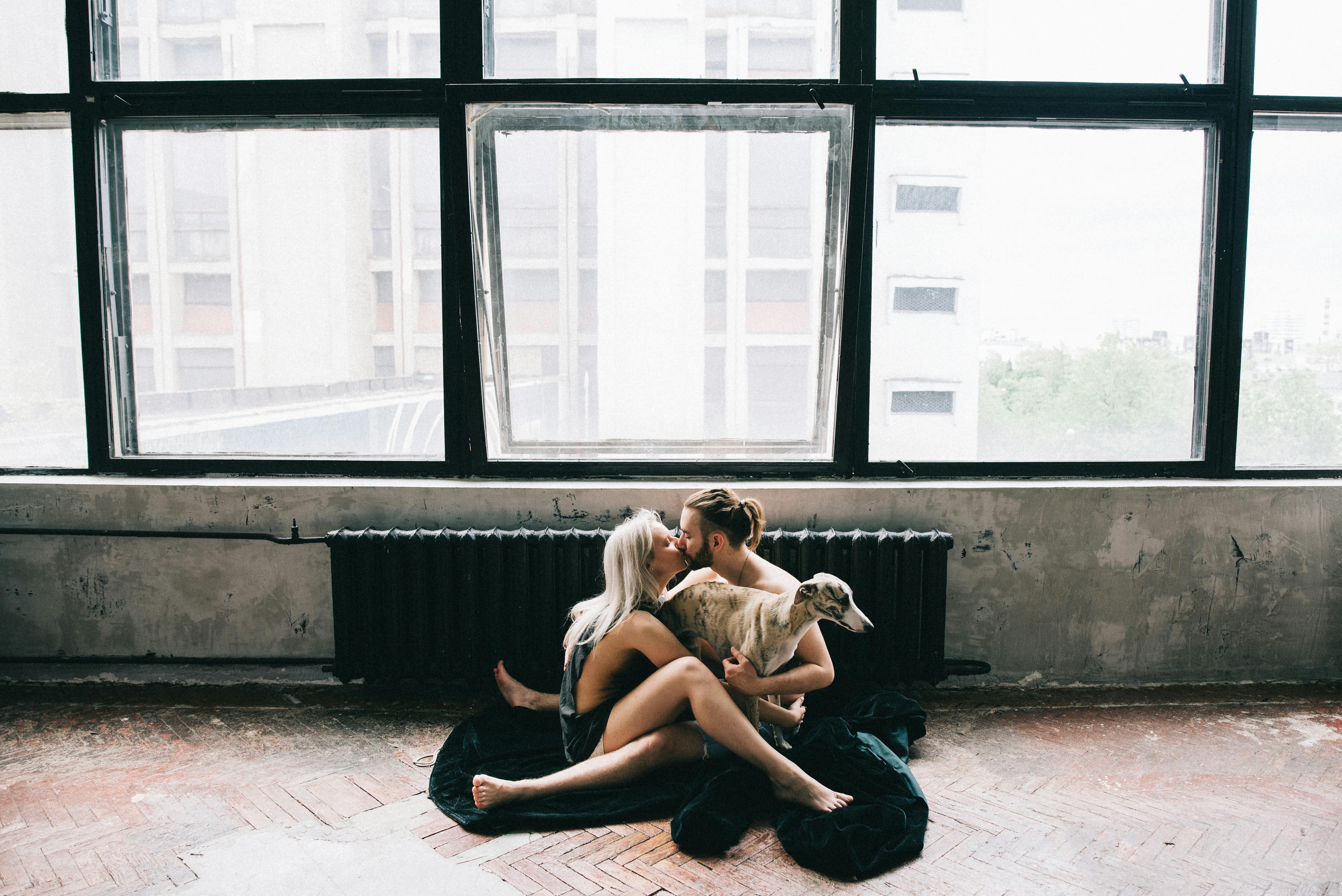 man and woman kissing and holding dog