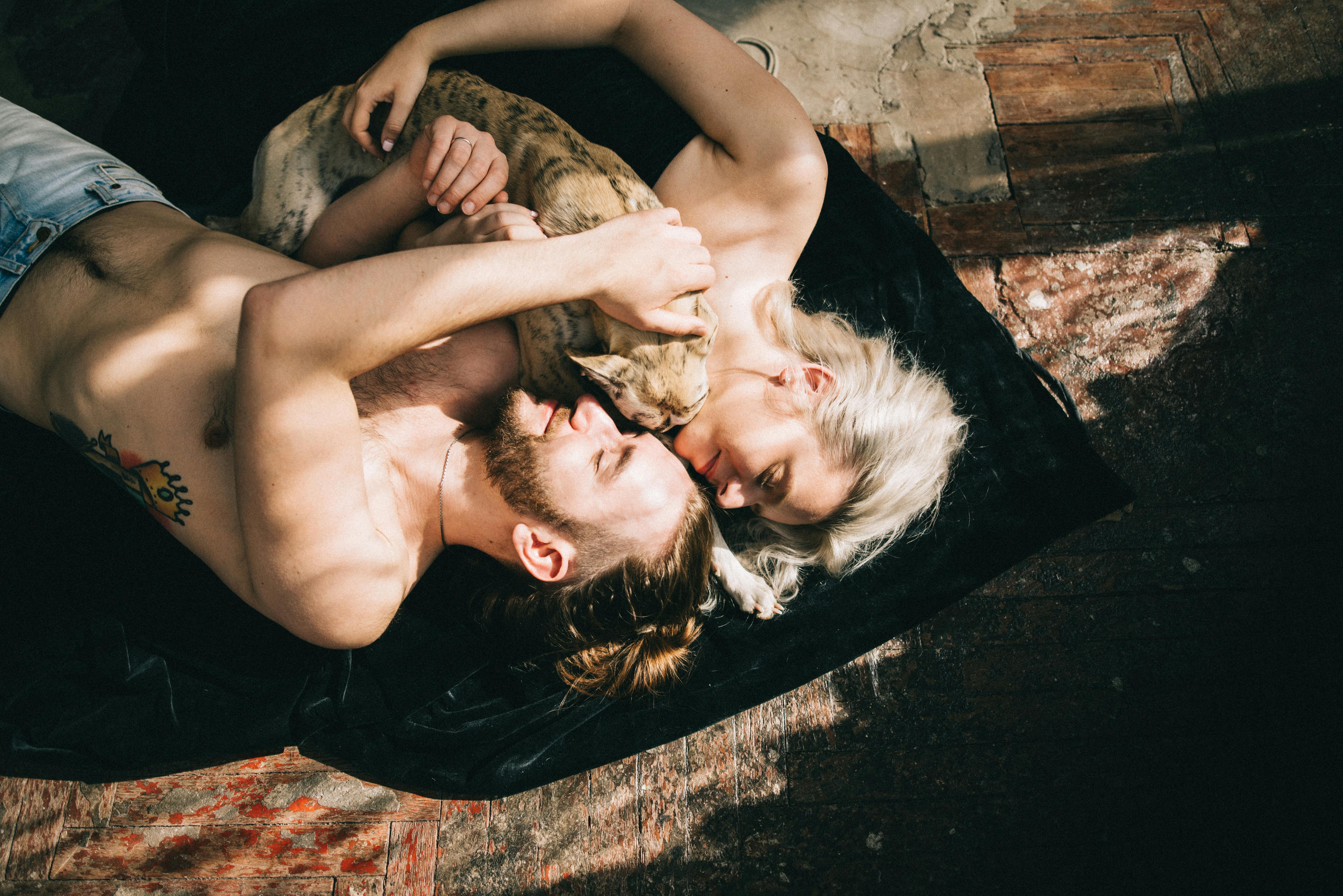 一对夫妇和他们的狗躺在室内的木地板上，惬意地享受着阳光