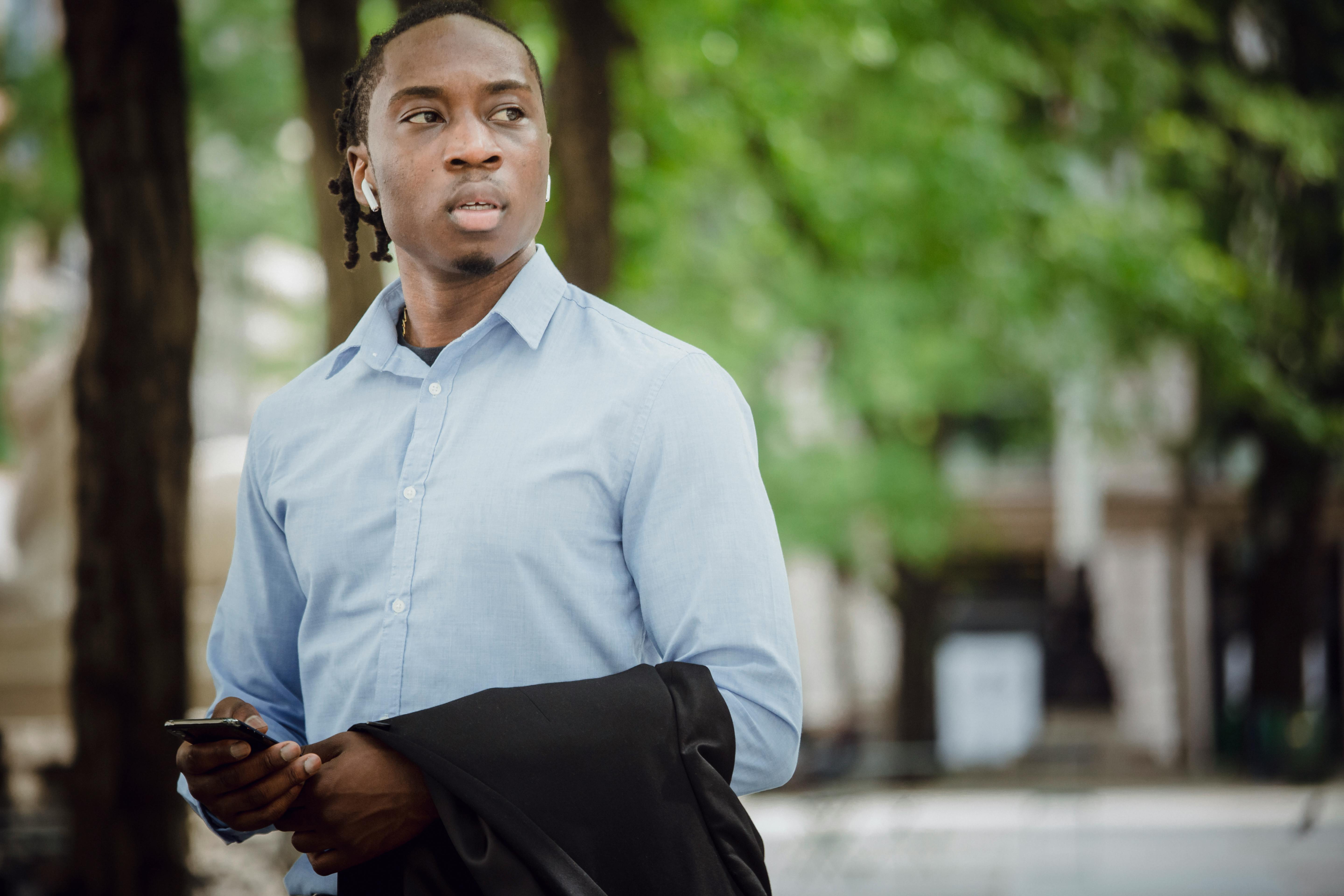 confident ethnic office worker with smartphone in park