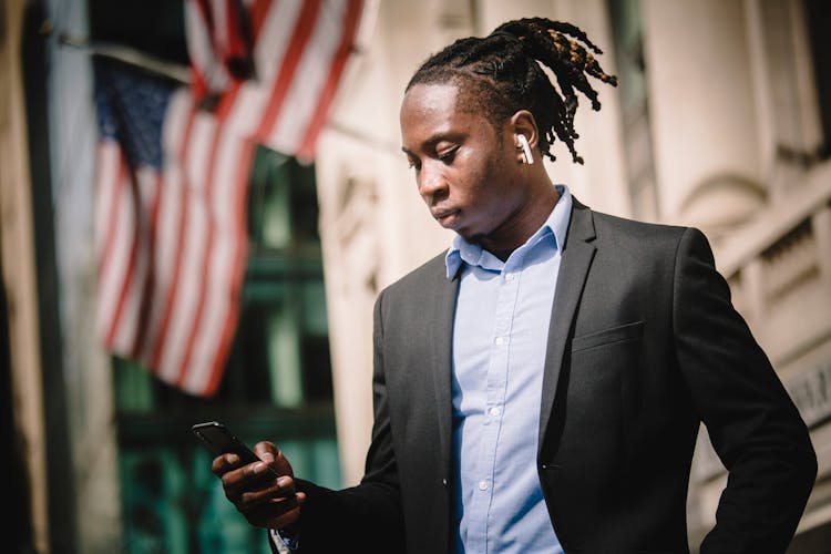 Serious Black Businessman Using Smartphone On Street