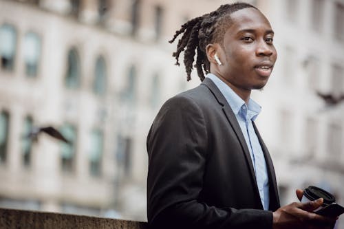 Positive black entrepreneur listening to music on city street