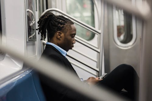 Serious male office worker using cellphone on subway train