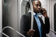 一位年轻沉思的黑人上班族在乘地铁回家时打着电话