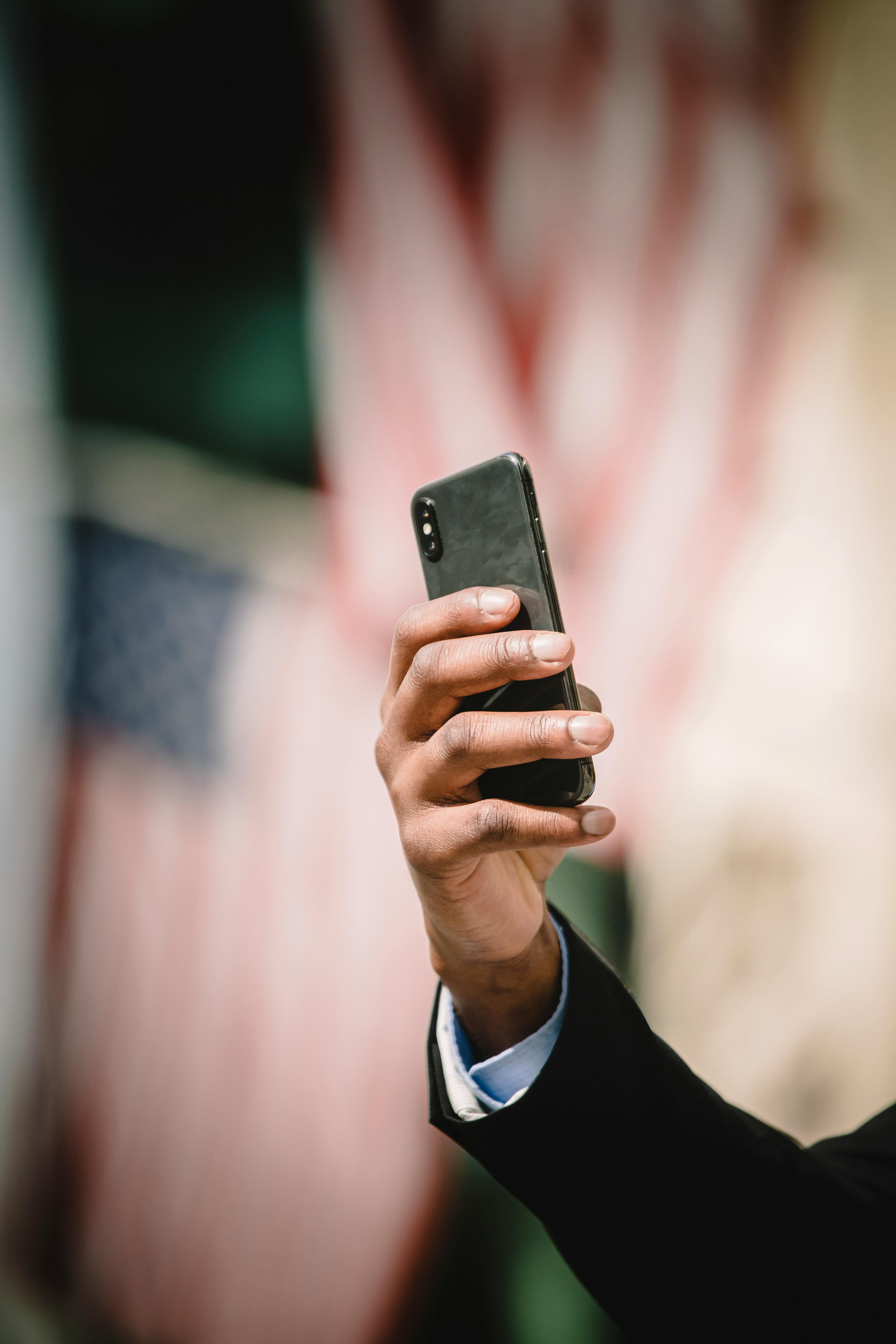 crop person using smartphone against blurred american flags