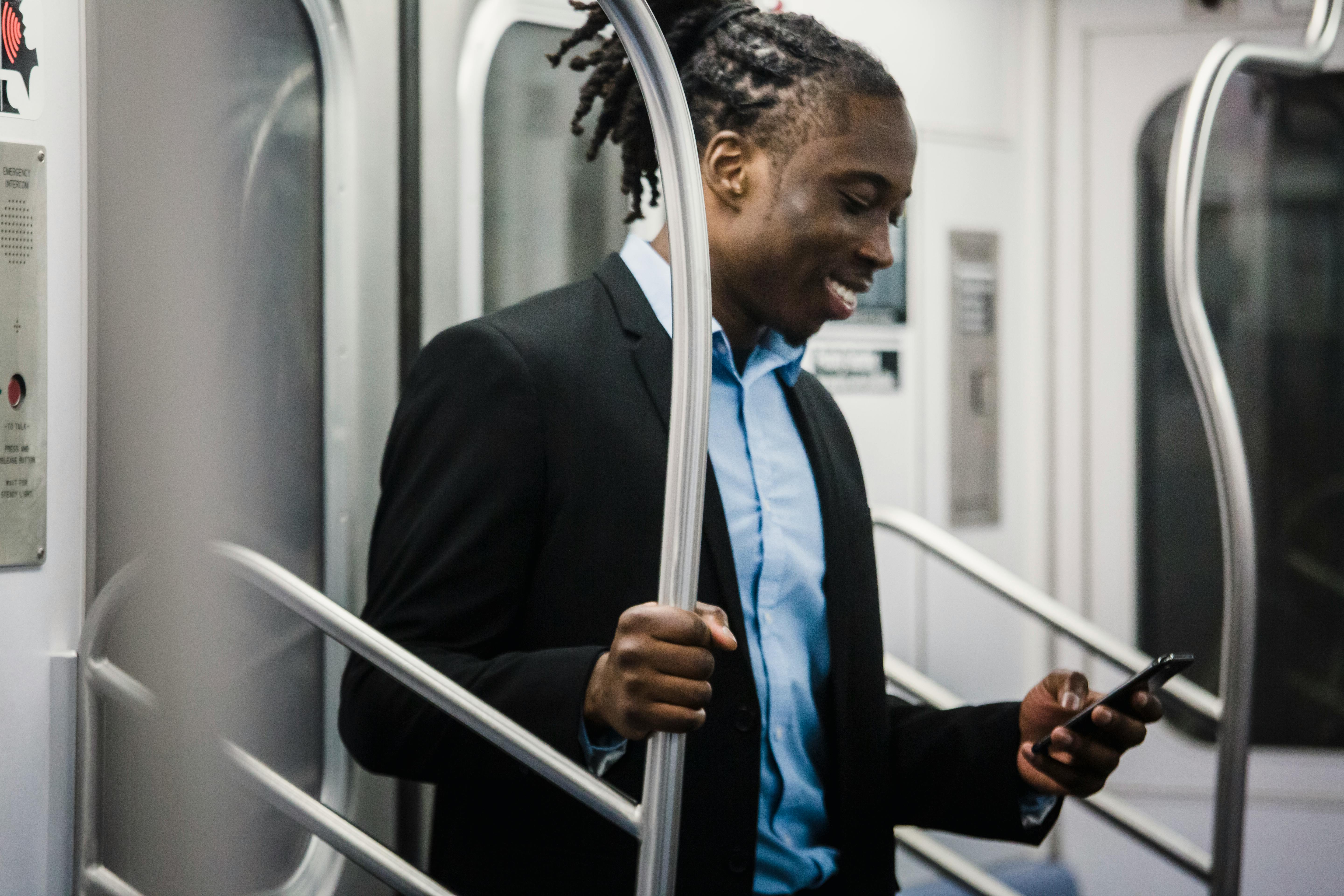 cheerful black man surfing net on mobile on subway train