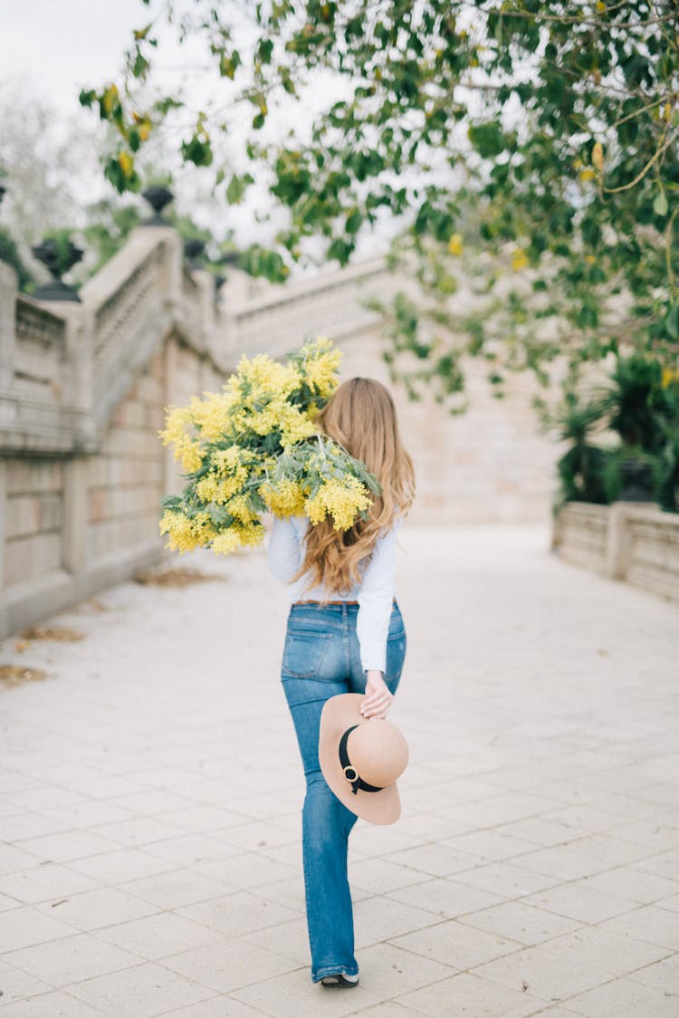 Woman Carrying A Bunch Of Yellow Flowers