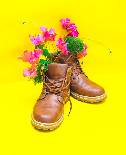 Modern leather boots with decorative flowers on yellow background