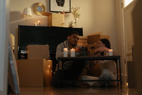 Free Couple enjoying a romantic evening indoors amidst moving boxes and candles. Stock Photo