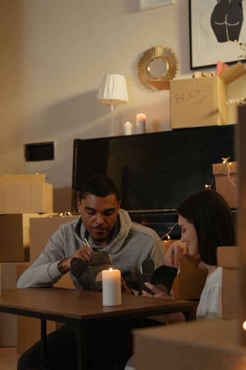 Free A young couple enjoys unpacking in their new apartment surrounded by moving boxes and warm candlelight. Stock Photo