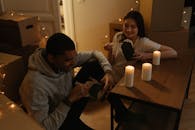 情侣在烛光下享用亚洲外卖，周围堆着移动的盒子，营造出舒适的氛围