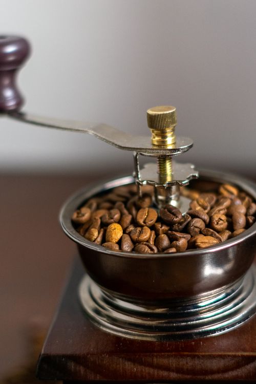 Free Close-up of a vintage coffee grinder filled with roasted coffee beans, showcasing its classic design. Stock Photo