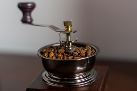 A close-up of a vintage coffee grinder filled with fresh coffee beans.