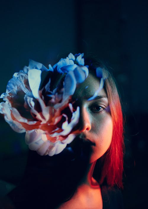 Free Calm young woman with flower in dark room Stock Photo