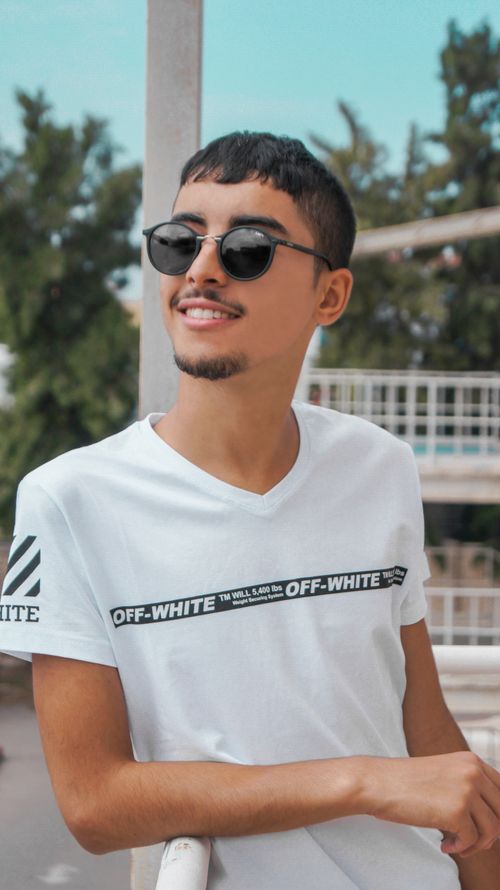 Free Portrait of a young man in sunglasses and casual wear, enjoying a sunny day outdoors in Mohammadia, Algeria. Stock Photo