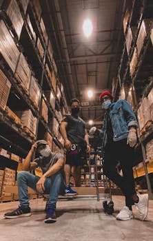 A diverse team of masked warehouse workers taking a break in storage facility.