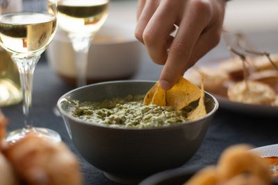 Hand dipping a chip into a bowl of green herb dip — photo by Pierre-Antoine Caisso on Pexels