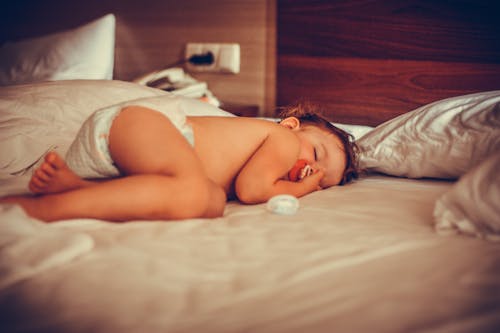 Free Innocent little child with nipple sleeping in bed Stock Photo