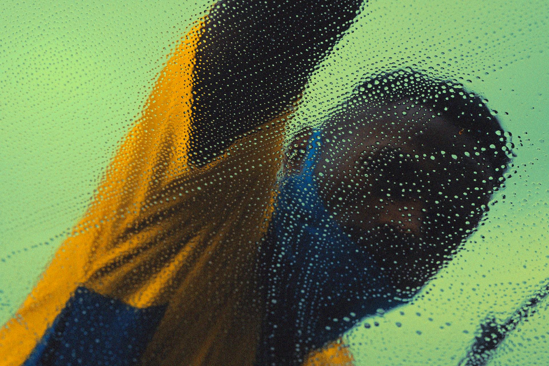 Unrecognizable black man washing windshield in daytime