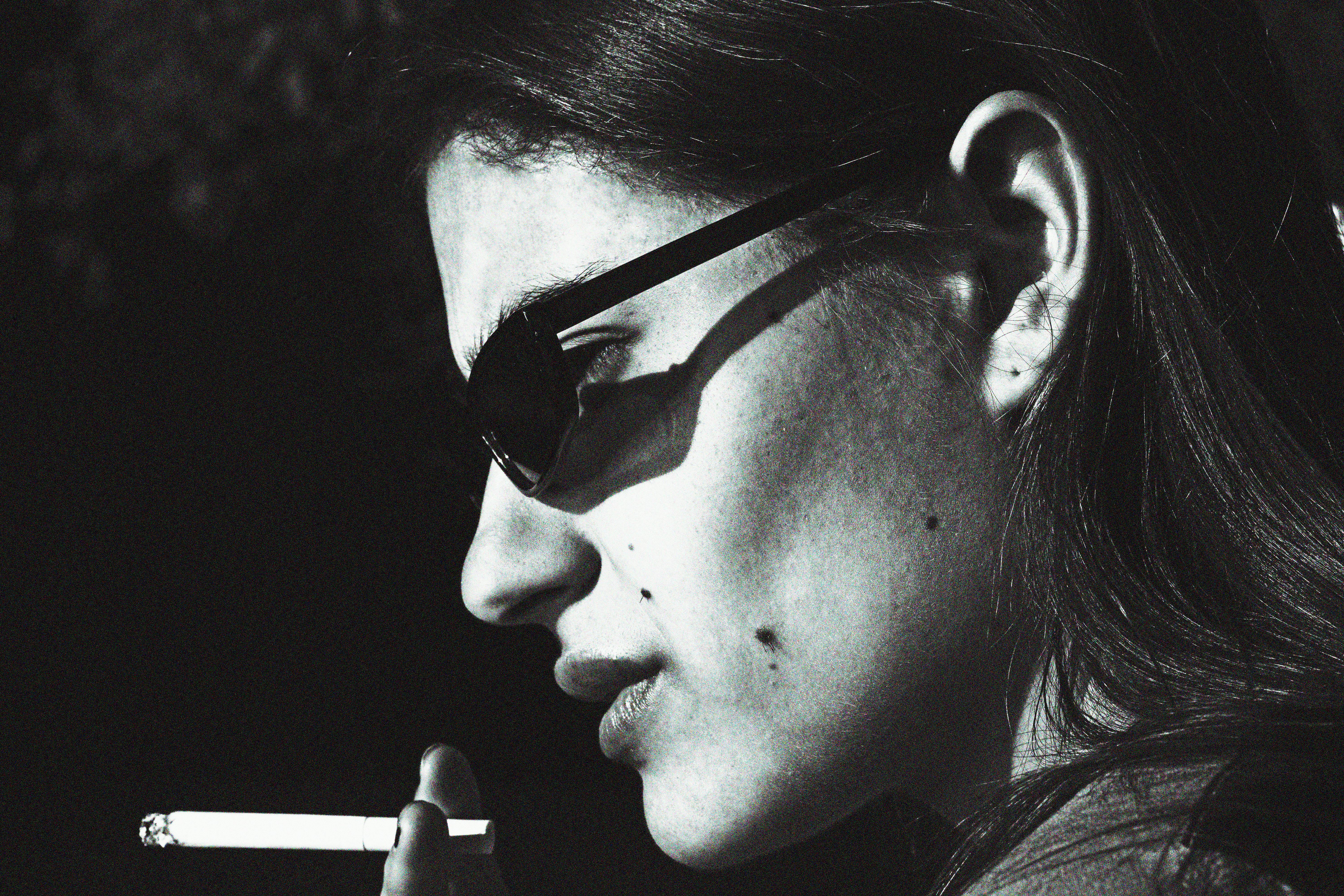 serious young woman smoking cigarette on sunny day