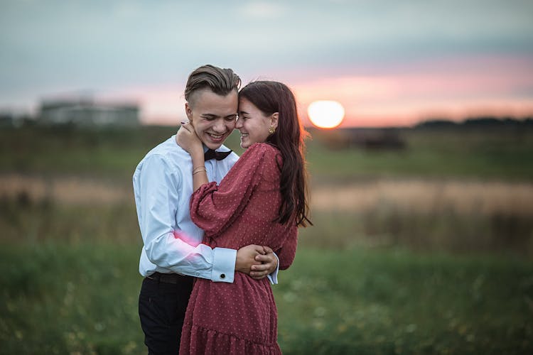 Happy Young Couple Embracing During Romantic Date In Nature At Sundown