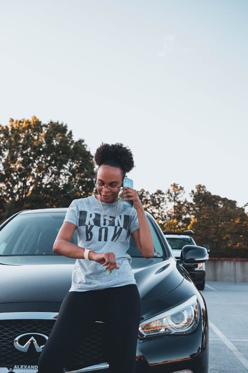 Black woman standing near black car