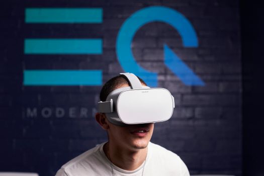 Adult wearing VR headset indoors, enjoying virtual environment. Smiling with immersive experience.