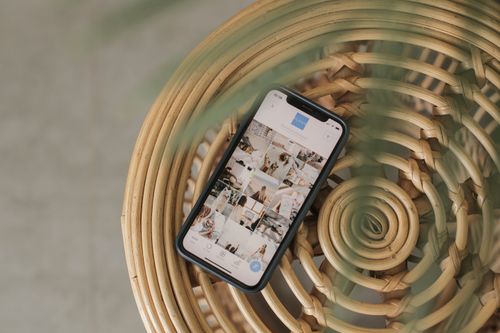 Free A smartphone displaying a social media app interface, placed on a wicker chair, creating a relaxed Bali vibe. Stock Photo