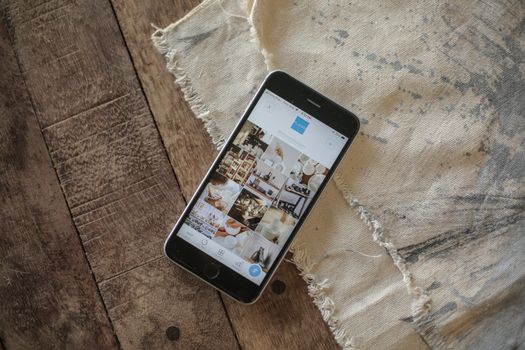 Modern smartphone with app open, resting on rustic wooden surface in natural light.