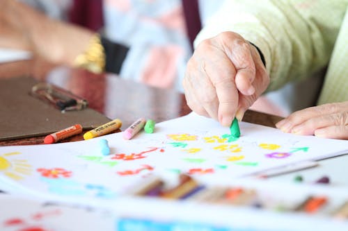Free Faceless elderly person with rheumatoid arthritis drawing with crayon during rehabilitation in nursing home Stock Photo