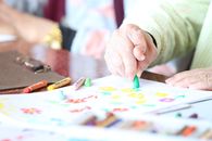Crop elderly patient with crayons