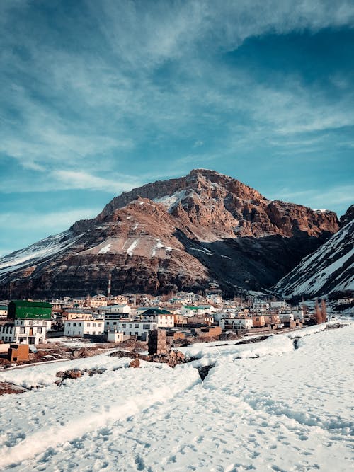 Snow covered terrain with town buildings on background of big mountain in sunny day