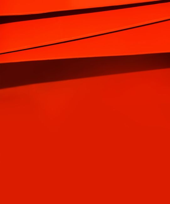 A vibrant red abstract image featuring dynamic geometric shapes and lines.