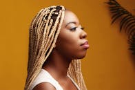 橙色背景下，一位扎着金色辫子的时尚女性肖像