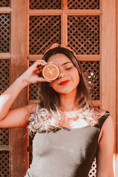 在里约热内卢乡村的木制背景下，一名妇女手持橙子切片的明亮肖像