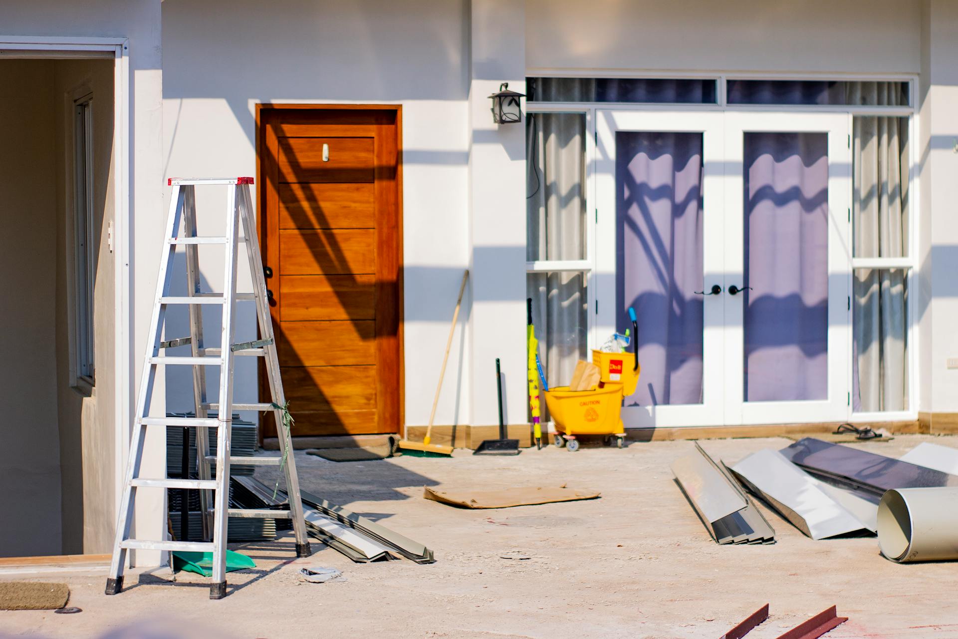 Front entrance of a house under renovation with tools and materials scattered around.