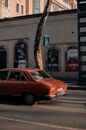 Retro car driving on city road near building