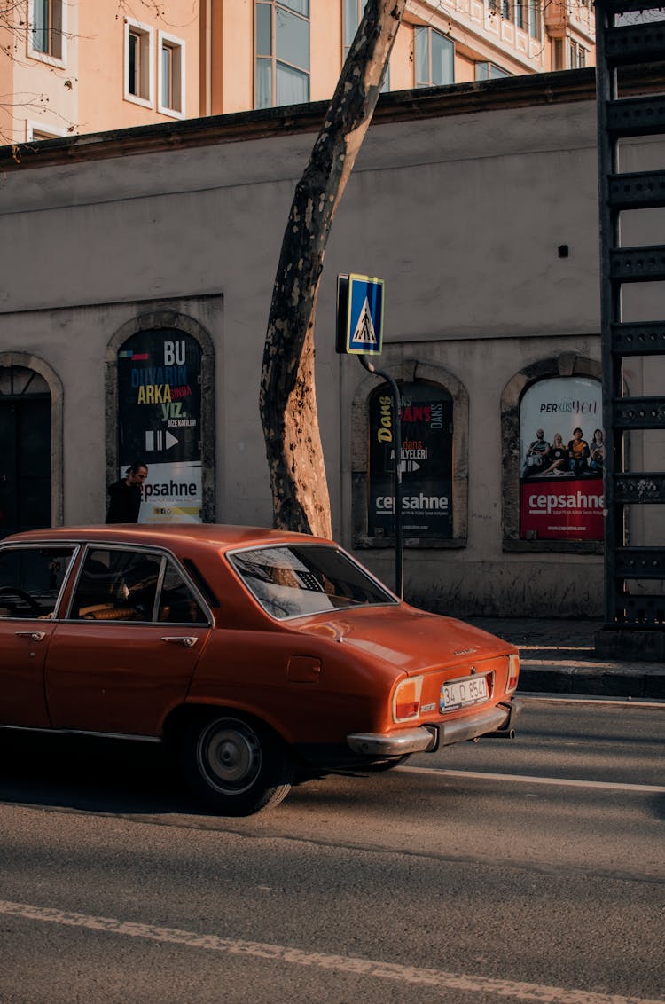 Retro Car Driving On City Road Near Building