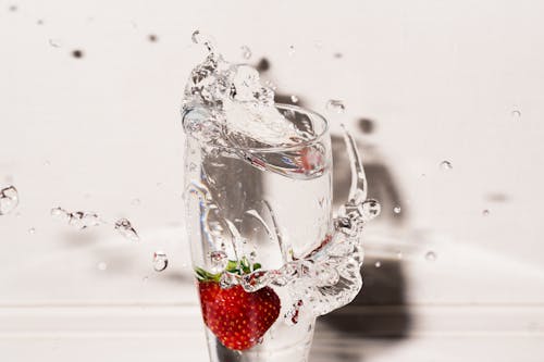 Clear Drinking Glass With Strawberry and Overflowing Water