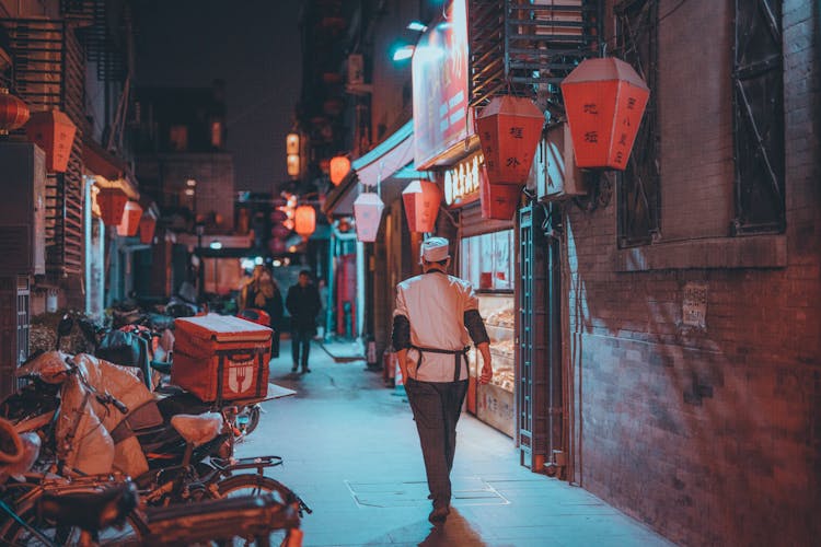  Man In Chef Uniform Walking In An Alley During Night Time