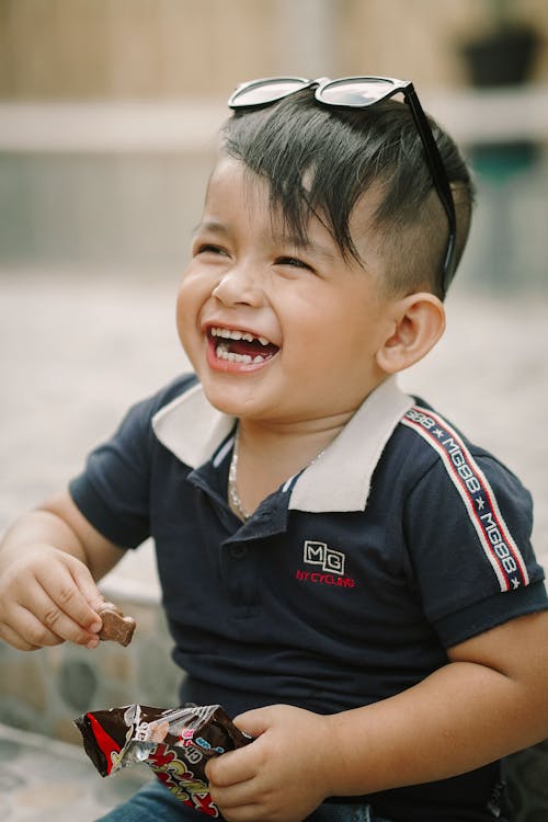 Free Boy in Blue and White Polo Shirt Holding a Chocolate and Smiling Stock Photo
