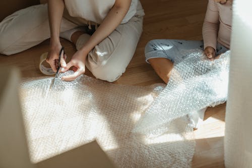 Woman in White Shirt and Blue Denim Jeans Sitting on Brown Carpet