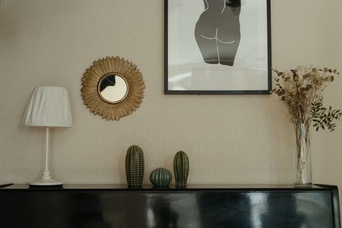 Free Elegant bedroom interior with decor elements like cacti, wall art, and a rustic mirror. Ideal for modern home inspiration. Stock Photo