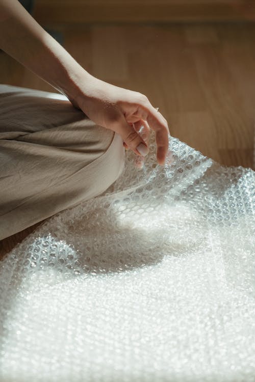 Person in Brown Pants Sitting on White Textile