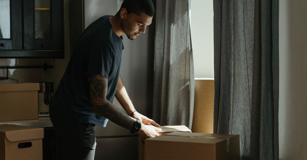 Millennials packing moving boxes in a small city apartment looking relieved