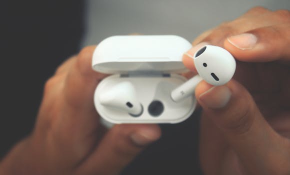 A close-up view of hands holding wireless earbuds in an open charging case.