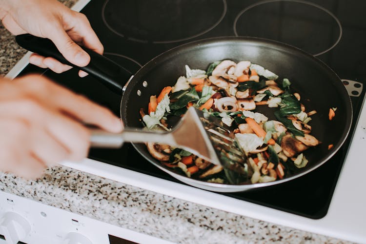 Person Frying Vegetables On A Pan