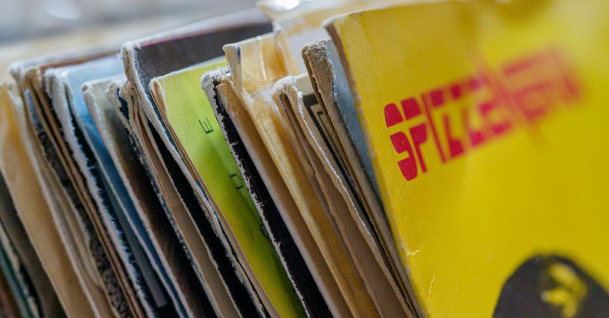 vinyl records stacked in a crate, close-up of colorful album covers